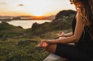 Une femme méditant au sommet d'une montagne, symbolisant les effets bénéfiques à long terme de la méditation pour la réduction du stress.