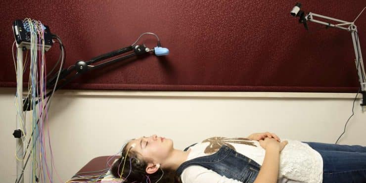 Une femme allongée pour une expérience sur le cerveau, illustrant les 5 impacts majeurs de la méditation de pleine conscience.