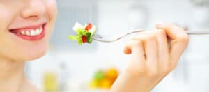 Une femme utilisant la pleine conscience en dégustant une salade, illustrant les façons faciles d'utiliser la pleine conscience pour maigrir.